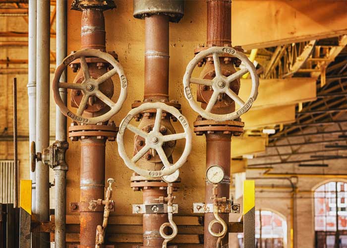 A long row of large, industrial-looking valves and pipes, conveying a sense of scale and complexity.