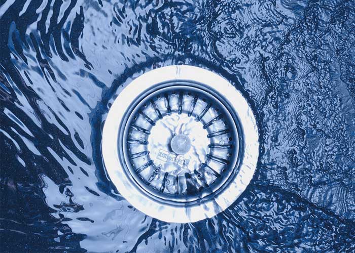 A close-up view of a white drain in the center of swirling blue water patterns