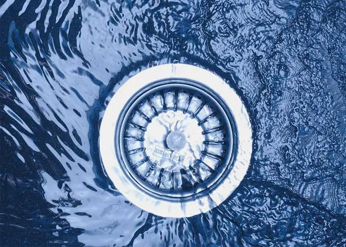 A close-up view of a white drain in the center of swirling blue water patterns