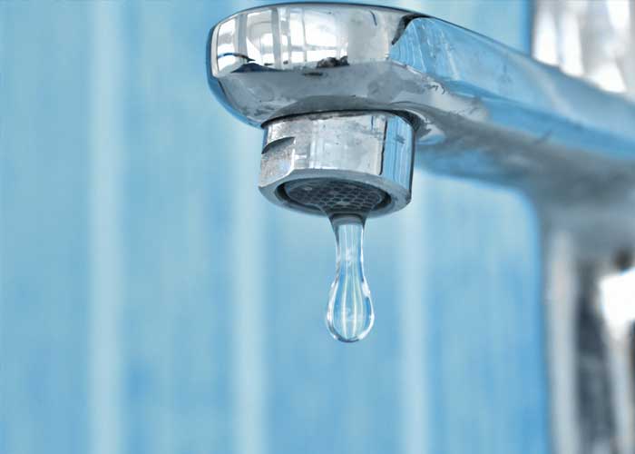 A faucet with water dripping from the spout, highlighting the flow of water.