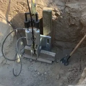 A custom-made tool or device used for construction or excavation, set up in a dirt or rocky environment.