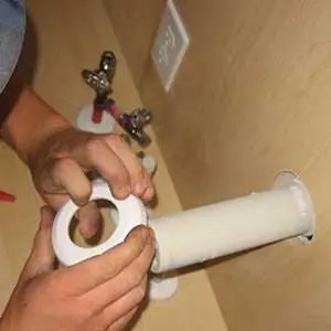 Hands using a plumbing tool to work on a PVC pipe or pipe fitting.