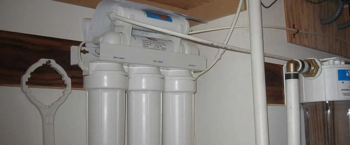 An image showing a water filtration system with multiple filters and attachments, mounted on a wall.
